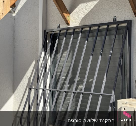 סורג מתכת עם בטן בצבע אפור המותקן על חלון חיצוני